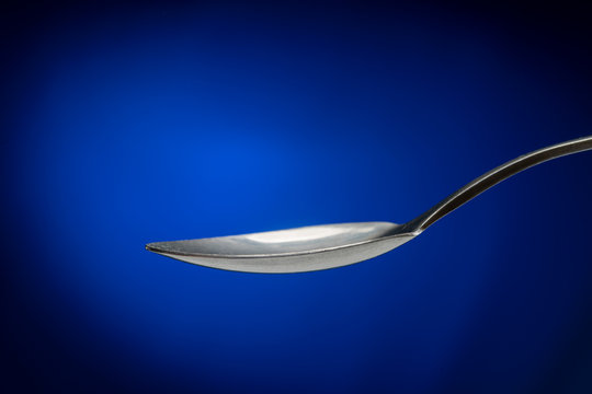 tablespoon on blue background closeup