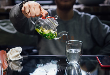 Hot green tea with mint, steam rises, dark background