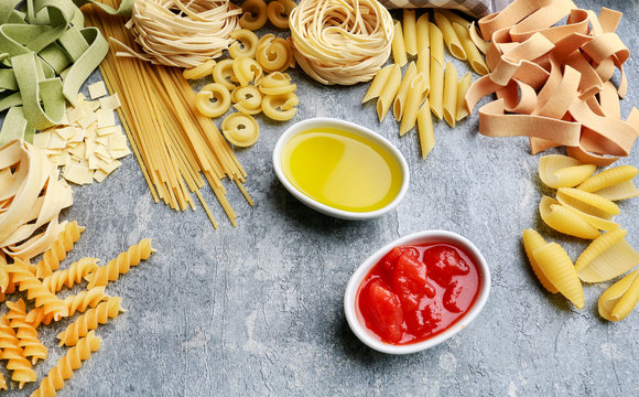 Mixed types and shapes of italian pasta on grey stone background
