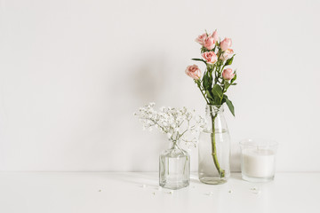 Naklejka na ściany i meble Roses, gypsophila and candle on table wall background. Romantic mockup template. Elegant minimalist