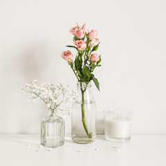 Roses, gypsophila and candle on table wall background. Social media or blog background