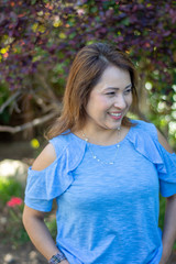 Fototapeta premium Latina Mother Smiling in Back Yard in front of red leaved bush