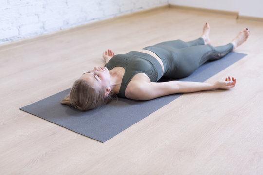 Woman laying on mat in relaxing pose on the floor. Yoga class, the shavasana.