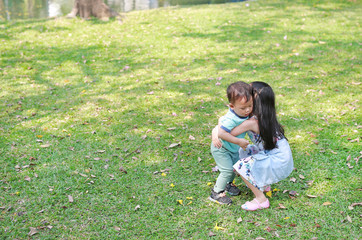 Fototapeta premium Asian sister carrying her little brother in the garden outdoor.