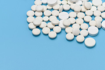 Lots of round white pills on blue background. Medication scattered on a blue background. Medical background. Health, Pharmacy, healthy lifestyle. Copy space for advertisement