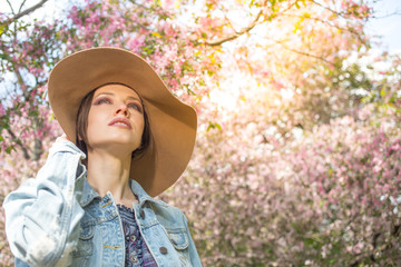 Young woman in spring park with blooming beautiful trees background