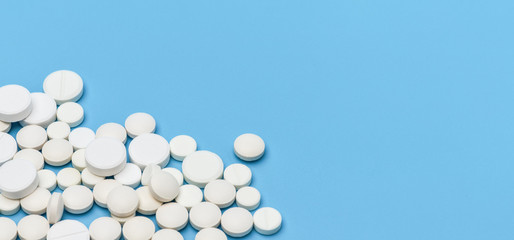 Banner. A lot of white round tablets on the bottom left on a blue background, on the right an empty space for an advertising signature