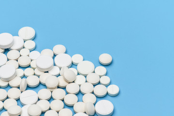 Lots of round white pills on blue background. Medication scattered on a blue background. Medical background. Health, Pharmacy, healthy lifestyle. Copy space for advertisement