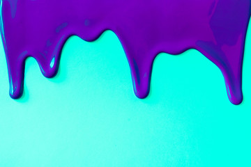 Blue paint leaking down cyan background. Close up.