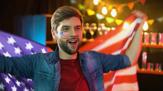 Happy american soccer fan waving national flag, cheering for favorite team