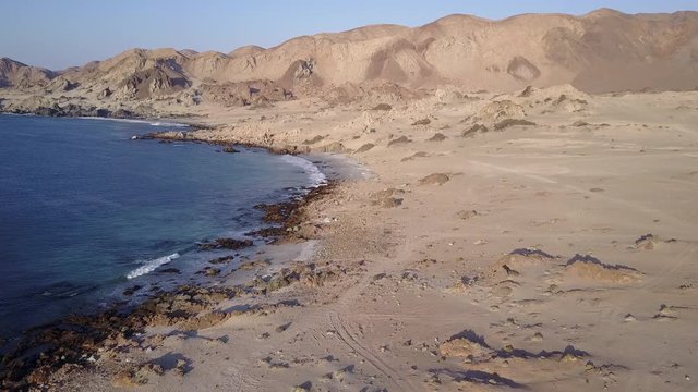 Las Tortolas beach aerial footage at Atacama Desert the sunset ray lights illuminate this amazing and idyllic beach in the middle of the desert, an arid awe landscape crashed by Pacific Ocean waters