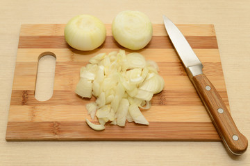 chopping board with onions and chopped onions with a knife