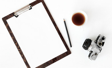 Top view of laptop, old camera, cup of coffee and notebook over white background