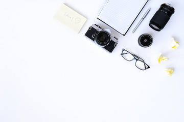 Creative flat lay photo of plain white desk with old camera, note book, pen glasses, sticky, Top view with copy space