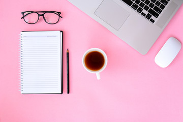 Office desk table with notebook,smartphone and coffee cup laptop. pink background flat lay top view