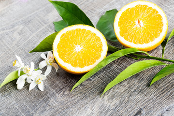 Juicy Orange cut in two parts and neroli, flowers of orange tree, on rustic wood background. The Orange blossom is the fragrant flower of the Citrus is used in perfume and tea, aphrodisiac.