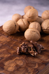 Bunch of walnuts on carved wooden board, bright background. Healthy nuts and seeds composition, background.