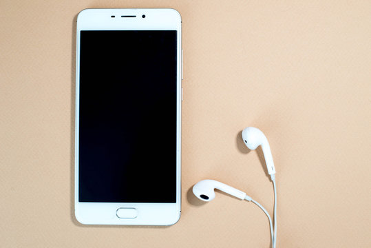White smartphone with headphones on pink background