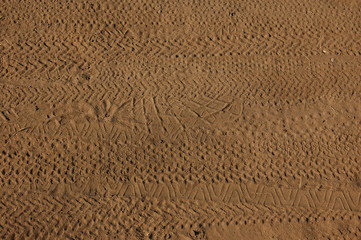 background horizontal traces of shoes and bicycle tires on the beige sand