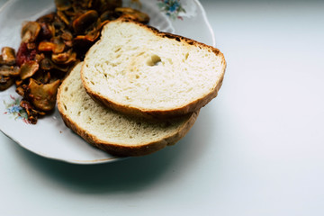 Fried mushrooms in a white plate with two pieces of bread