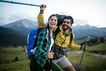 Backpackers happy young couple hiking with sticks