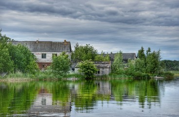 Gloomy landscape of old stone houses, gray rain clouds and reflecting coastal water