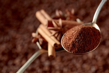 Spoons of ground coffee and anise with cinnamon sticks.