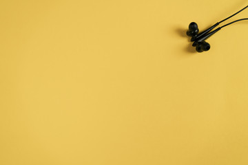 Black headphones on a yellow background Flat lay top view