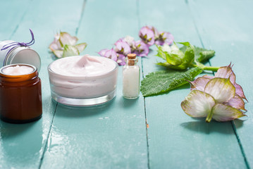 cosmetic creams and clary flowers on blue wooden table