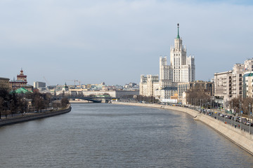 Fototapeta na wymiar River embankment overlooking the bridge and the tall white building of Stalinist architecture