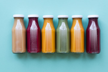 Fruit and vegetable juice bottles isolated on blue background. Natural Organic Food Style.