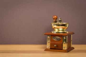 Vintage manual coffee grinder on wooden table with color wall background