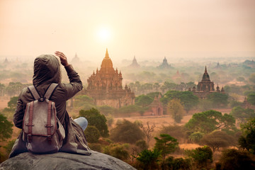 The tourist sitting watching Bagan pagoda landscape view during sunrise and the ancient pagoda in Bagan,Mandalay Myanmar - Powered by Adobe