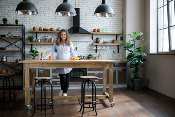 Portrait of a pregnant woman drinking orange juice while watching the house, is in the kitchen.