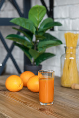 Orange juice in a glass on the kitchen table, fruits and oranges, healthy food.