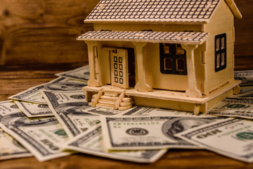 Plywood model of the house and one hundred dollar banknotes. Loan, real estate concept