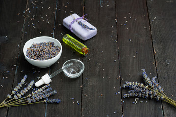 perfume, essential oil, soap and dried lavender flowers on black wood table background