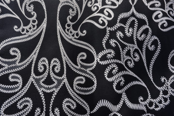 Tissu noir brodé de motifs frises blancs