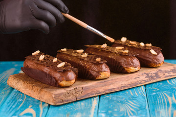 Delicious chocolate and peanut eclairs on a blue wooden table