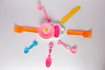 Many colorful plasic forks, spoons and knives on white background with copy space, top view. Devices for baby food