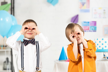 adorable preteen boys looking at camera through fingers during birthday party