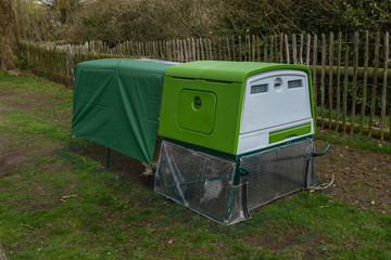 A three quarter shot of a green modern bright looking chicken coup or hen house with covered top