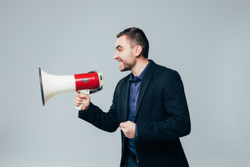Portrait of young businessman shouting with megaphone against a white background
