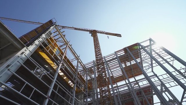 Construction of logistic buildings, bottom up view of steel floors and construction crane, camera motion.