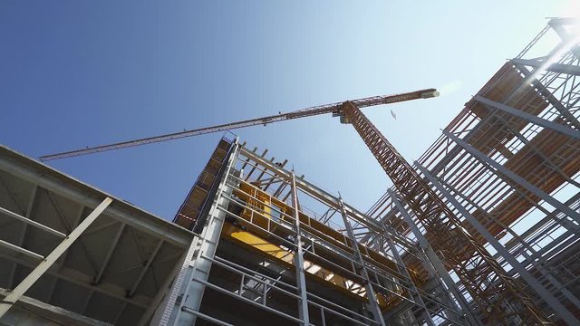 Construction of logistic buildings, bottom up view of steel floors and construction crane, camera motion.