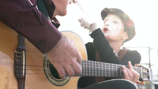 Two mimes on the street singing and playing guitar