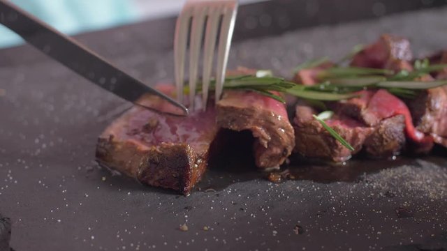 Filet Mignon is cut on a plate. Girl eating filet mignon.