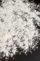 White flour is poured on a black table before cooking cookies