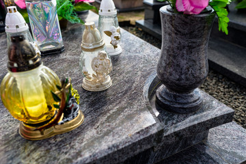 Candlesticks and a vase with flowers lying on a marble, dark tombstone.