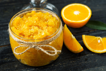 Orange homemade jam or scrub on a dark wooden table in a glass jar